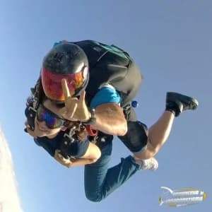 Paracadutista in caduta libera con casco a visiera specchiata, ripreso da vicino